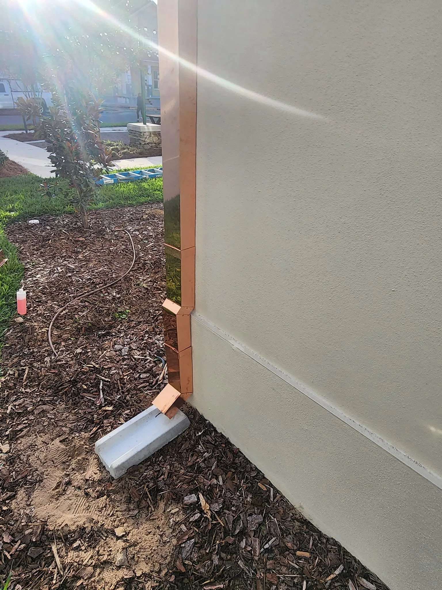 Copper downspout base elbow mulch bed stucco corner, Sanford